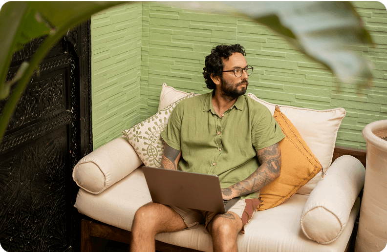 Two people sit next to each other in front of a table, on which there are a laptop, some pens and some pieces of paper