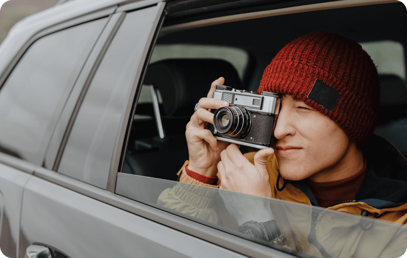 A guy taking a picture with his camera from the inside of a car.