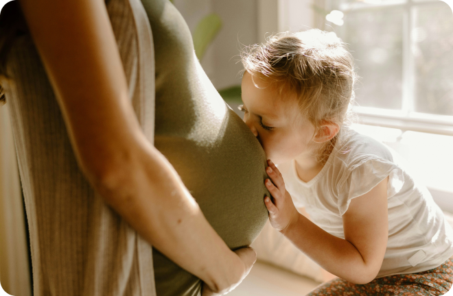 A kid kissing the belly of his pregnant mom