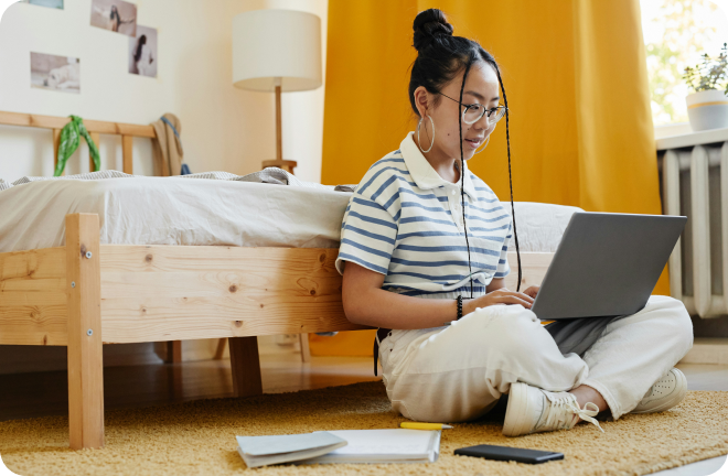 Student sitting next to her bed with her laptop