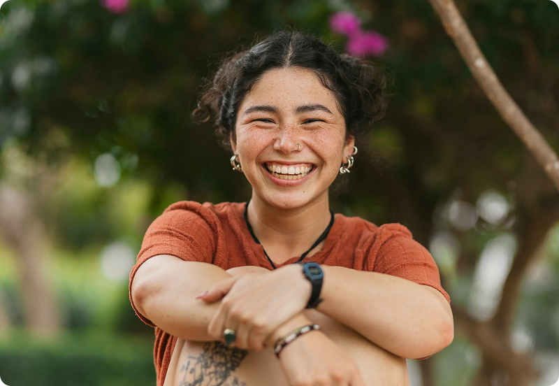 Girl sitting in a park, smiling joyfully.