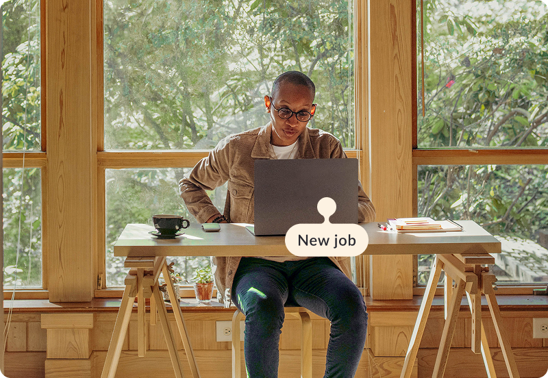 Person working at their desk, at home on a laptop. The tag reads "New job".
