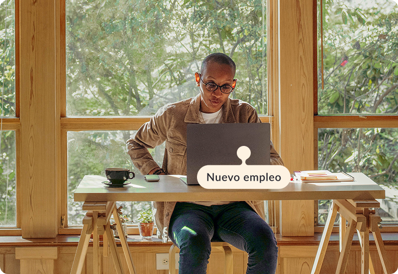 Persona trabajando en su escritorio, en casa con una computadora portátil. La etiqueta dice "Nuevo empleo".