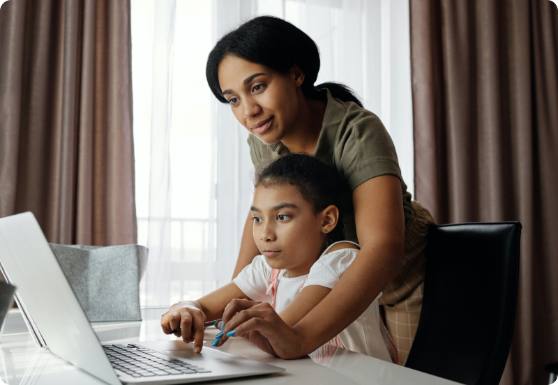 Mother and her daughter doing homework on laptop-