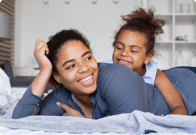 Mother and daughter laying on the bed.