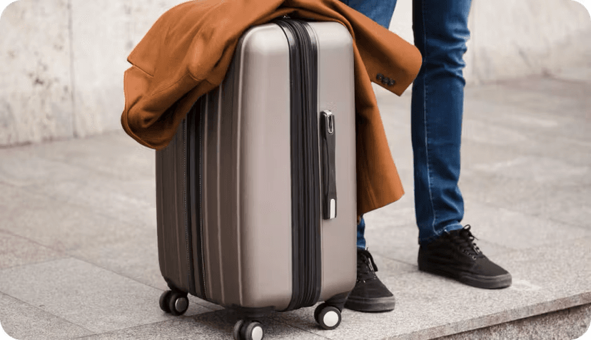 A person waiting with a suitcase by the curb.