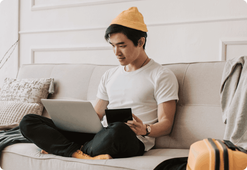 A man sitting on the couch checking insurance on his laptop.
