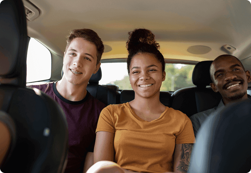 Friends sitting at the back of the car on a road trip.