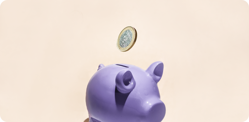 A single euro coin in mid-air above a purple piggy bank, set against a light beige background.