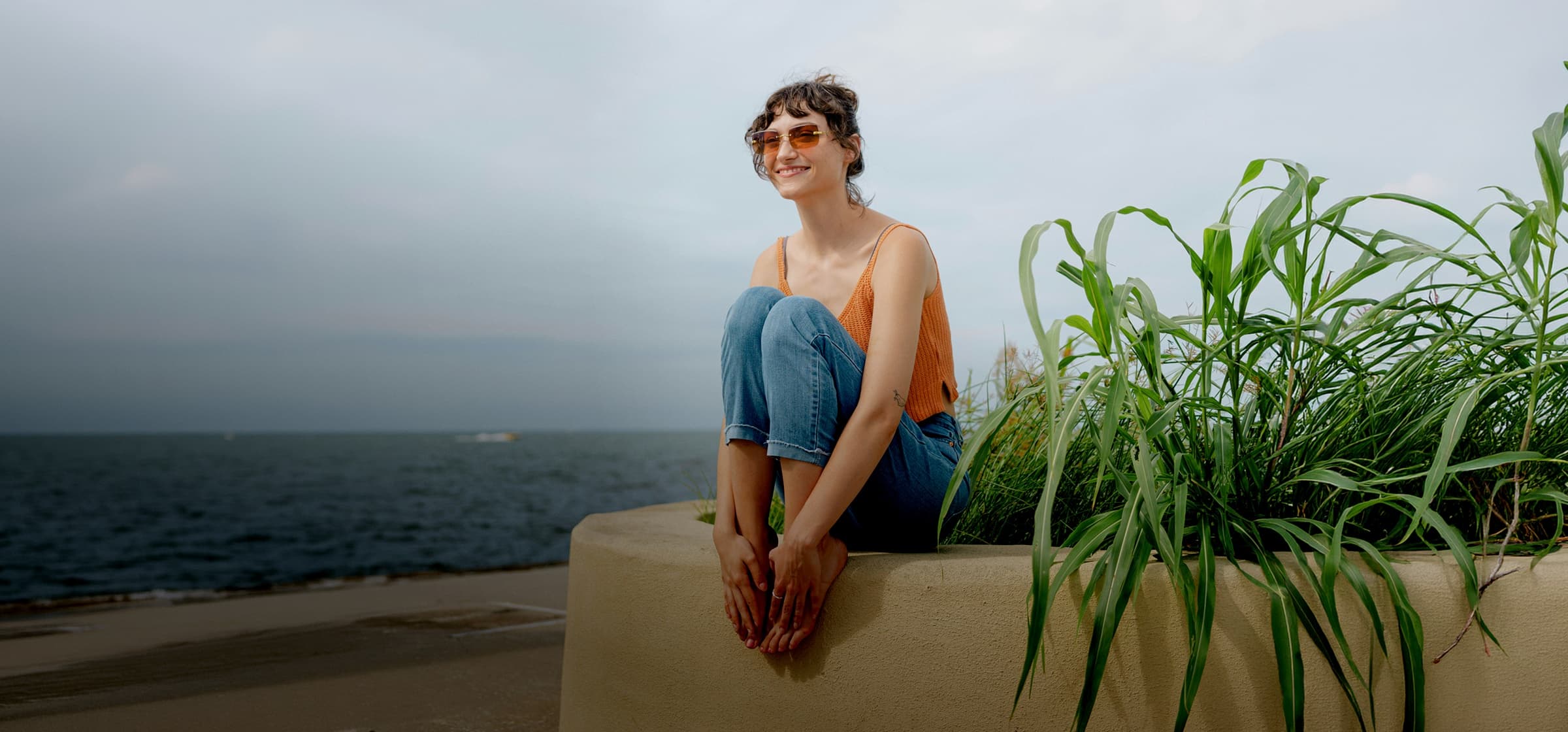 A woman sits by the sea in Cameroon, waiting for her expat health insurance confirmation of purchase.