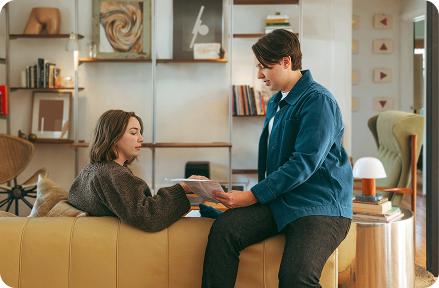 Two people in their cosy apartment, sitting on a couch and talking.