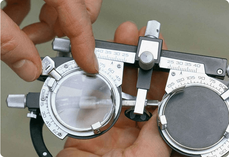 A close-up of an optometrist adjusting a trial lens frame used for eye exams, with hands delicately fine-tuning the dials.