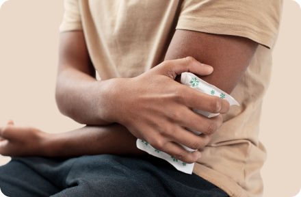 Person in a beige shirt holding an ice pack against their injured elbow