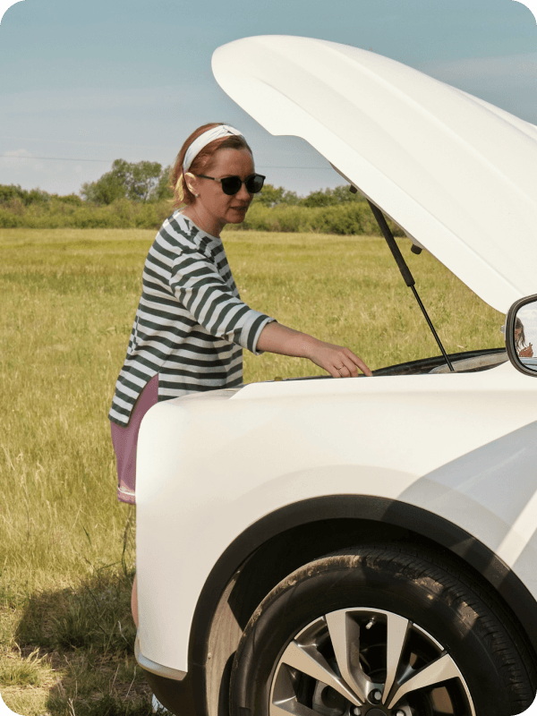 A woman attending a broken car out of the way.