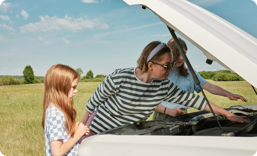 A mother and two daughters checking the engine of a white car parked with opened front bonnet.