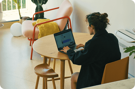 Persona sentada en una mesa trabajando en una computadora portátil.