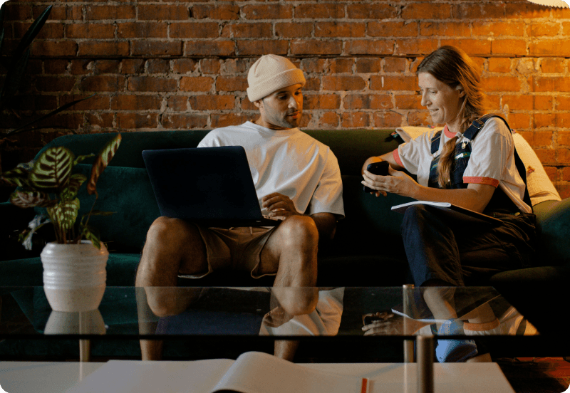 Two people sitting on a couch, and scrolling through Feather app, buying expat health insurance in Malta.