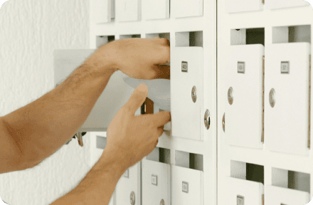 A person checking a mailbox in an apartment building.