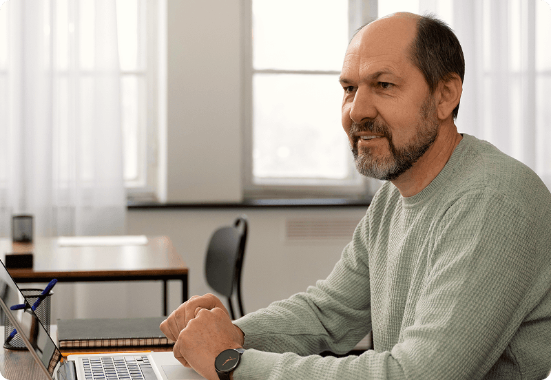 A middle-aged man sitting in front of a laptop.