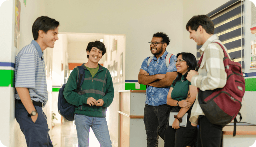 A group of student standing in a school hall, talking and smiling.