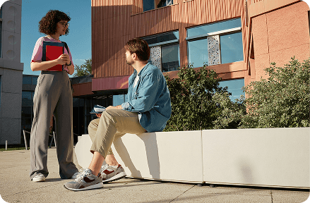 Two students talking in front of a university building.