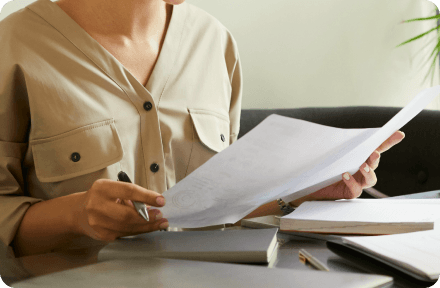 Person checking details on documents laying in front of them on a table.
