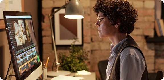 A woman working at her desk, in front of a computer screen, editing a video.