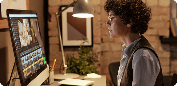 A woman working at her desk, in front of a computer screen, editing a video.