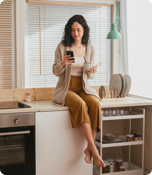 A picture of a person that sits on their kitchen table with a cup of coffee and a phone.