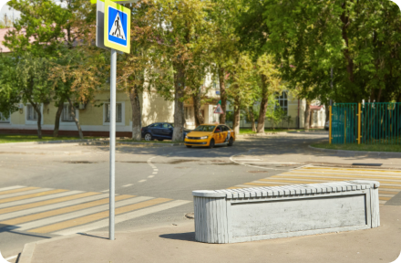 A car road in a city with a pedestrian crossing and cars parked on a side of the street.