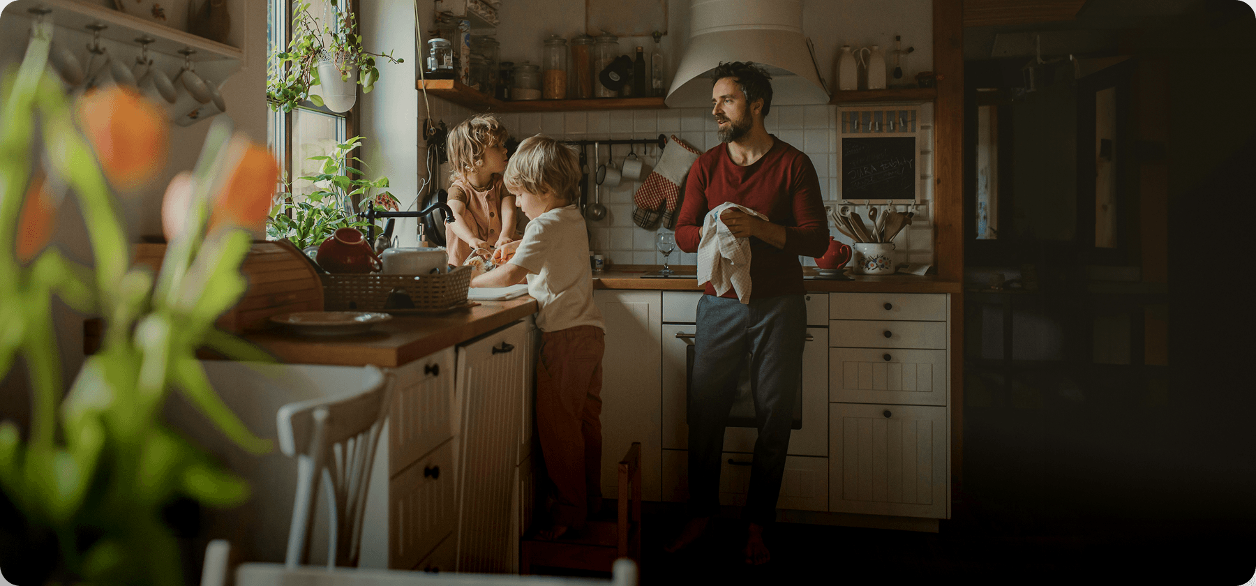A father and two young children doing the dishes together in a warm, homely kitchen in Spain.