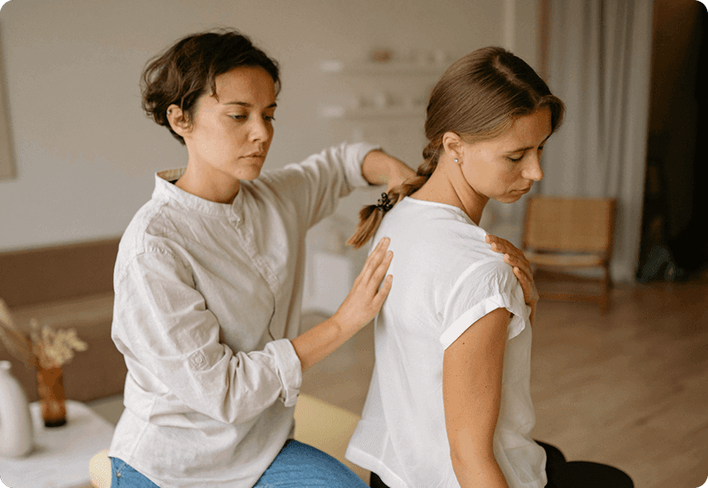 Woman exercising at a physiotherapist office, assisted by a specialist.