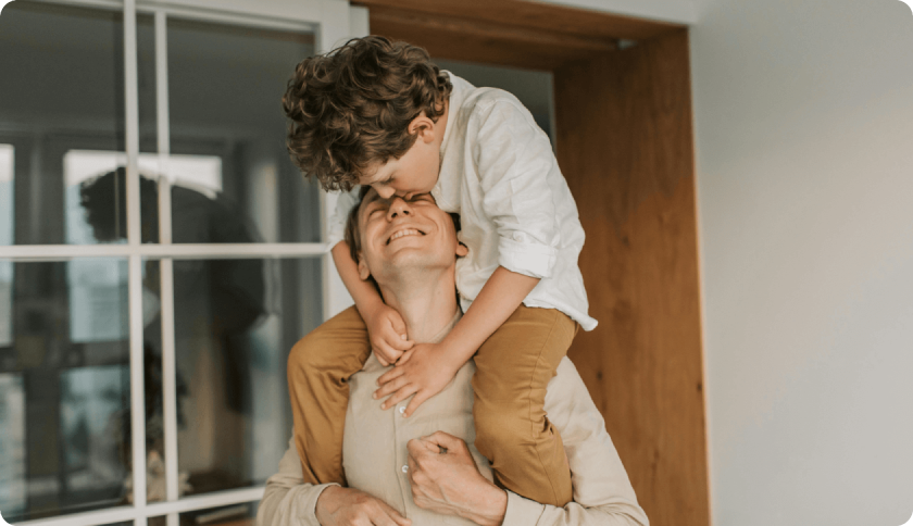 Man caring his son on his shoulders, smiling.