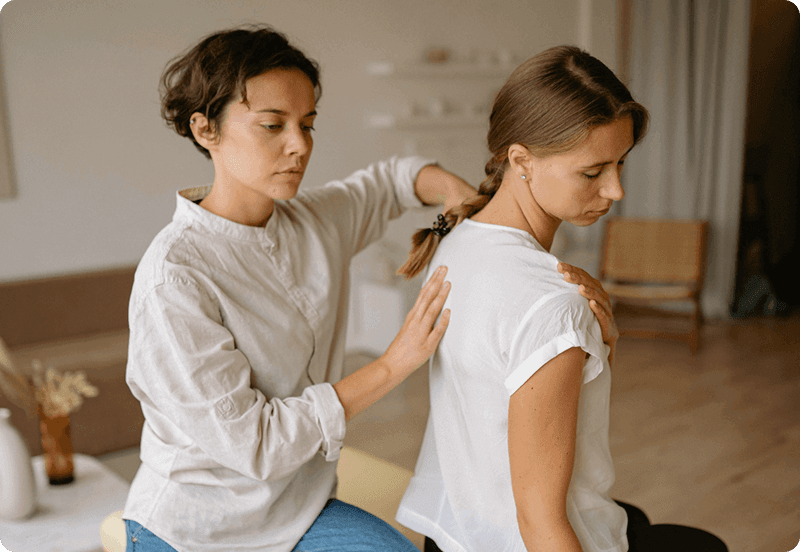 Woman exercising at a physiotherapist office, assisted by a specialist.