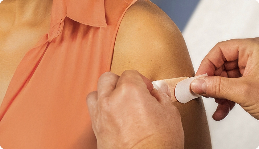 A doctor putting a bandage on patient's arm after a vaccination.