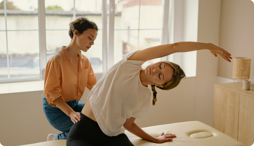 Woman exercising in a physiotherapist office, assisted by a specialist.
