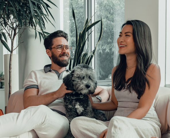 A woman and a man sitting in a couch holding a dog