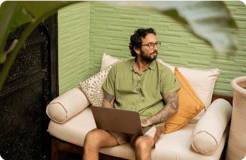 Two people sit next to each other in front of a table, on which there are a laptop, some pens and some pieces of paper
