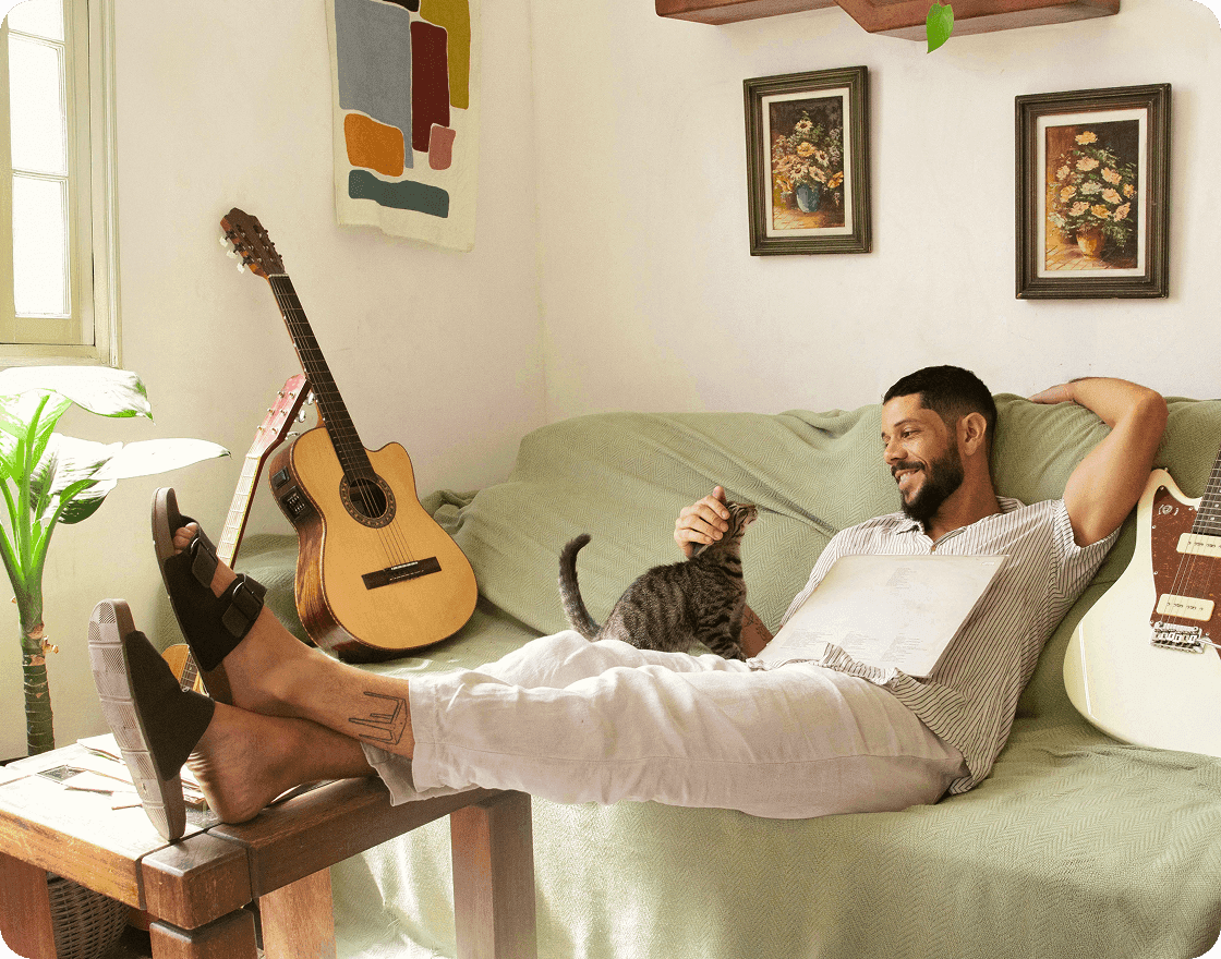 A man sat on a couch while petting a cat