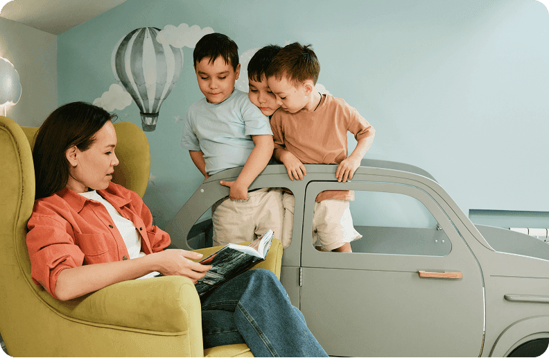 A woman who is holding a smartphone and a child sit next to each other on a couch while smiling
